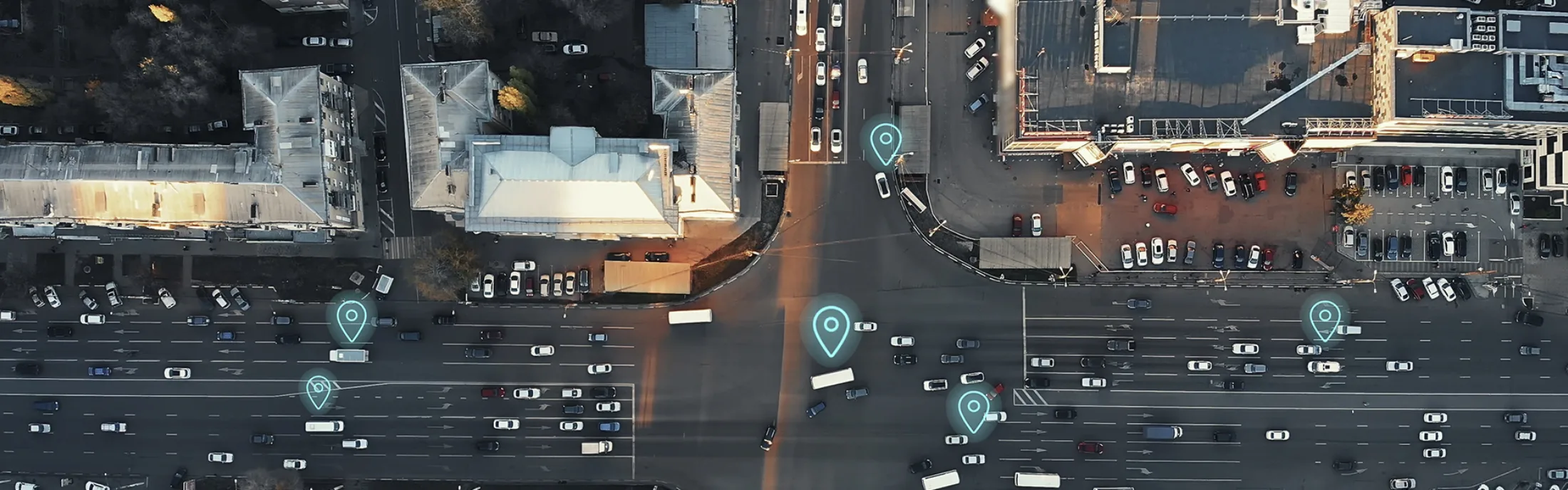 Aerial view of a busy city intersection with multiple cars, marked with digital location icons, representing GPS tracking or navigation.