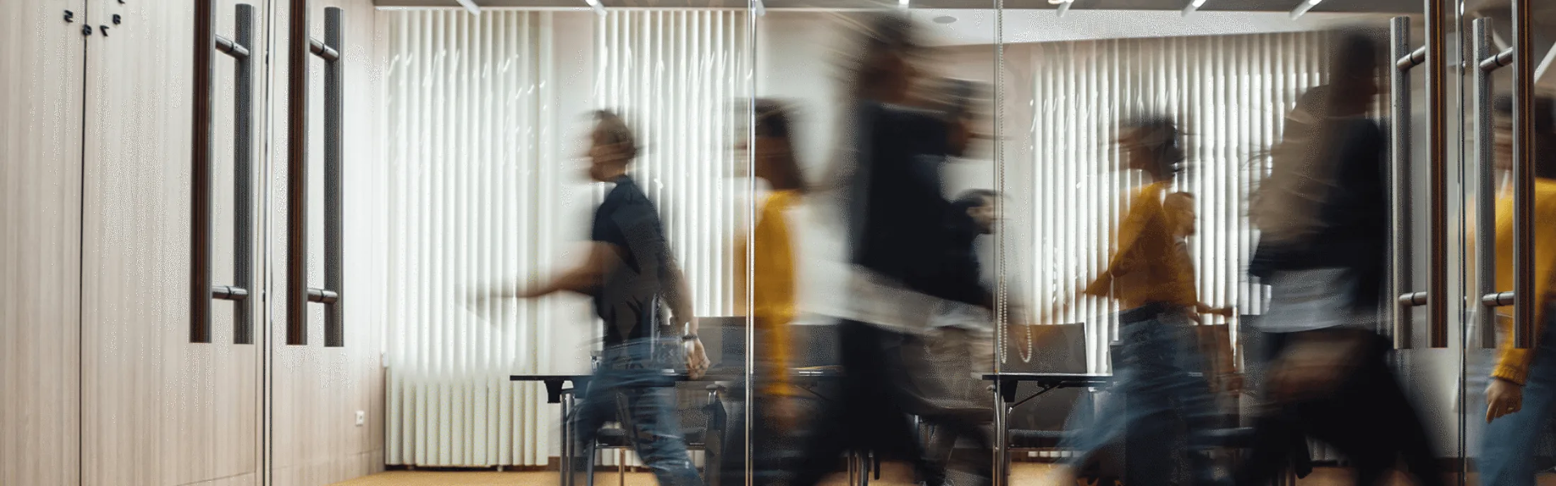 Blurred motion of people walking in an office hallway, reflecting a busy and dynamic work environment.