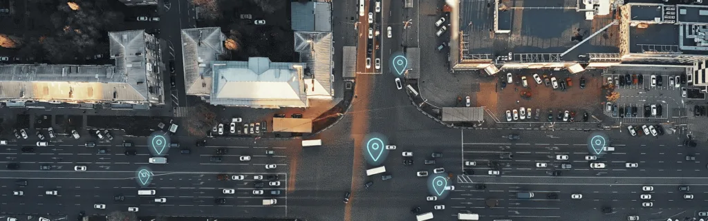Aerial view of a busy city intersection with multiple cars, marked with digital location icons, representing GPS tracking or navigation.