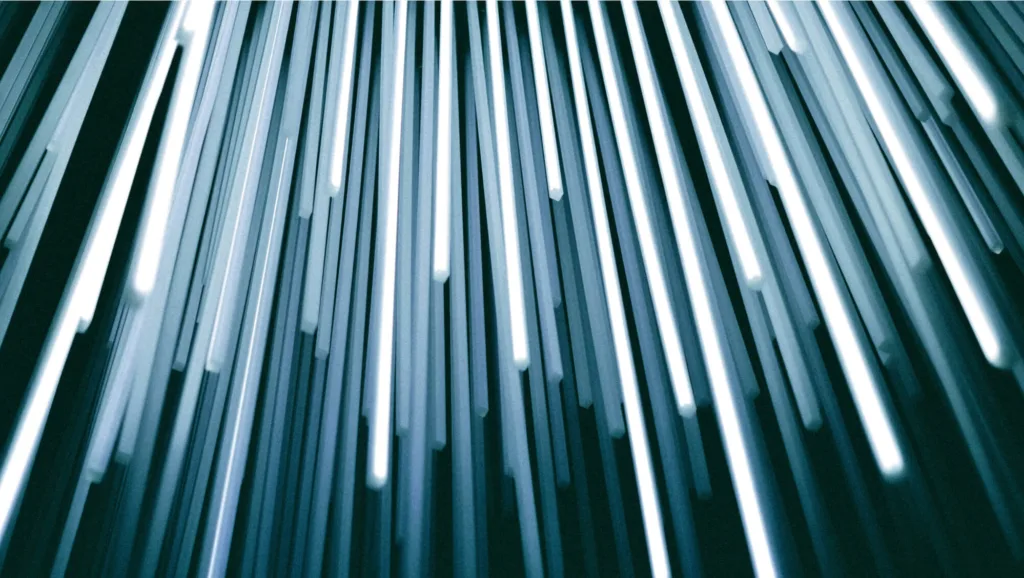 Abstract display of bright, streaking white and blue lights resembling fast-moving beams or digital data streams.